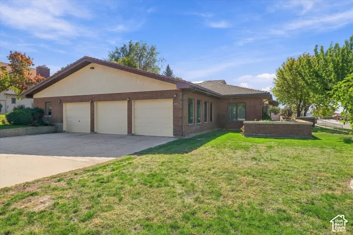 Brick exterior with stucco accents, three-car garage, concrete driveway, and a partially covered tiled roof