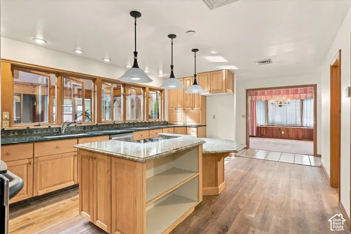 Kitchen featuring new LVP wood-finish flooring, pendant lighting over the island and cooktop in the island