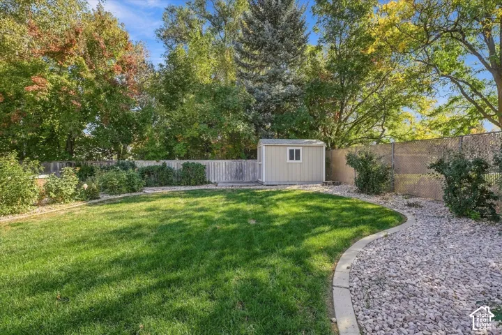 Expansive lawn area, mature trees, gravel pathway, garden shed, and a combination of wood and chain-link fencing