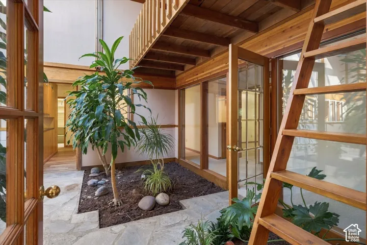 Central courtyard featuring natural stone paving, mature plantings, and a wooden overhead walkway