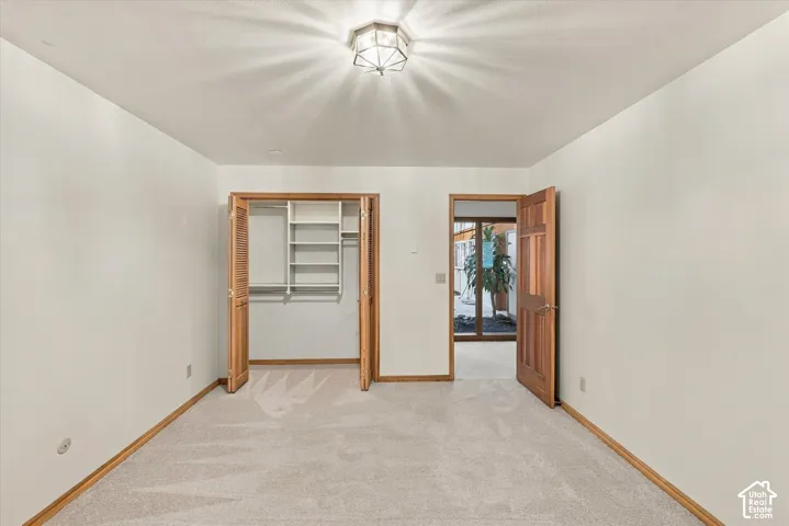 Spacious bedroom with warm wood-finish door frames, neutral carpeting, and abundant natural light