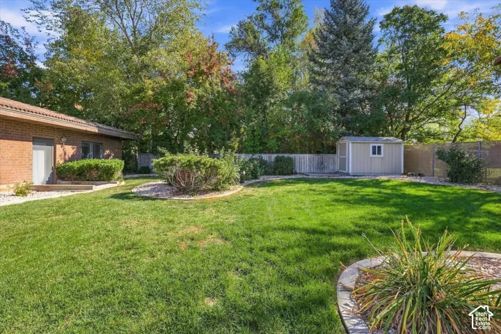 Expansive green lawn with established landscaping, brick exterior, and a detached storage shed