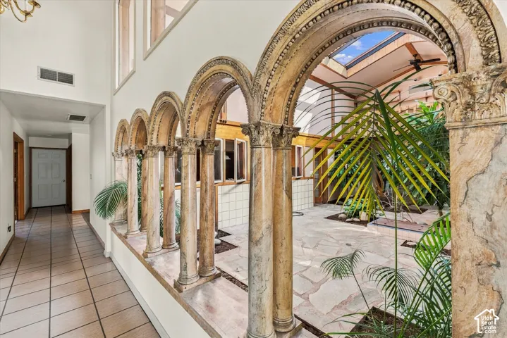 Architectural arched stone columns, stone tile flooring, interior skylight, and high ceilings