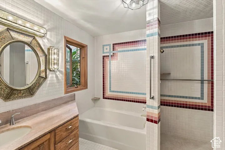 Bathroom featuring white square tile, wood-finish vanity with an integrated sink, octagonal mirror, and a window with wood trim