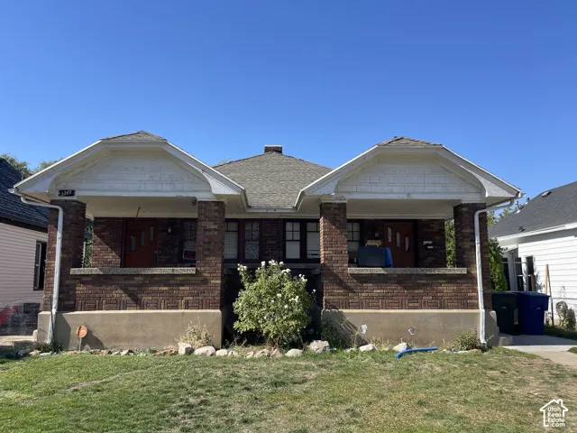 Brick facade with dual covered entryways, each featuring a pitched roof and decorative shingle siding