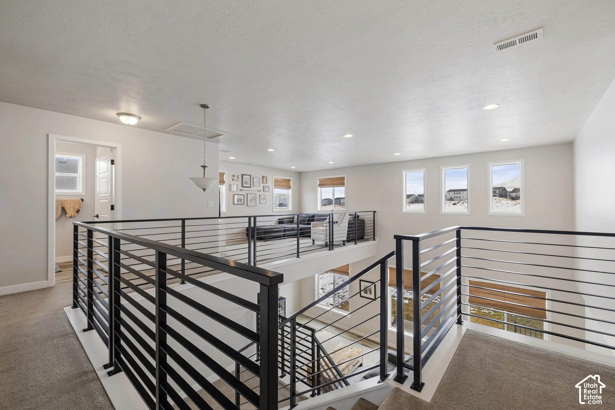 Open loft area with contemporary metal railings and recessed lighting