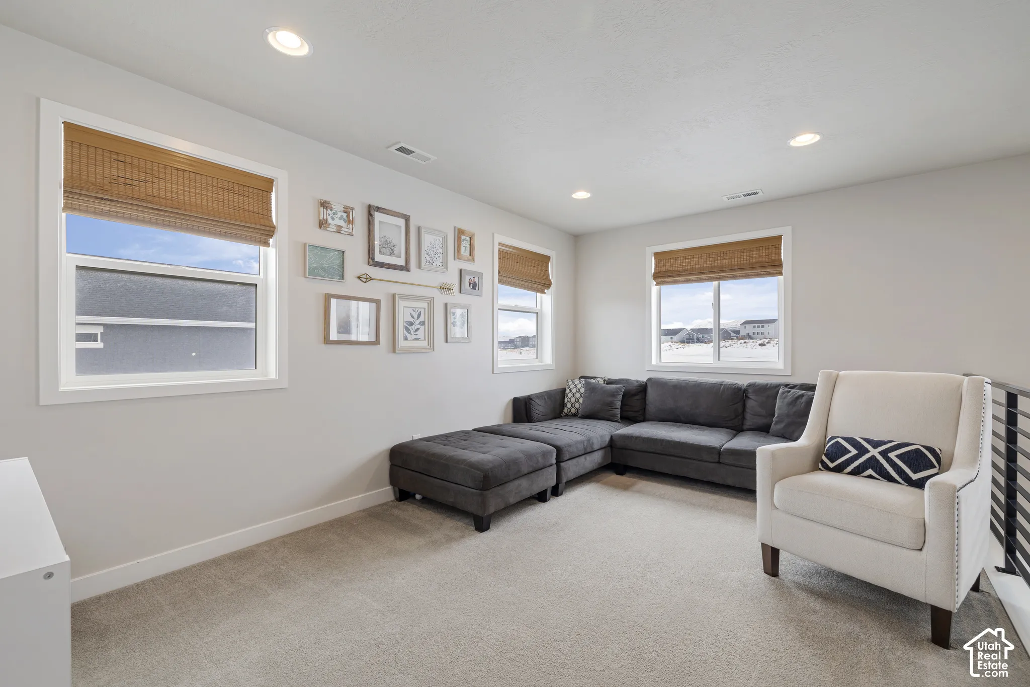 Recessed lighting, light-toned carpeting, multiple windows with blinds, and white wall finishes
