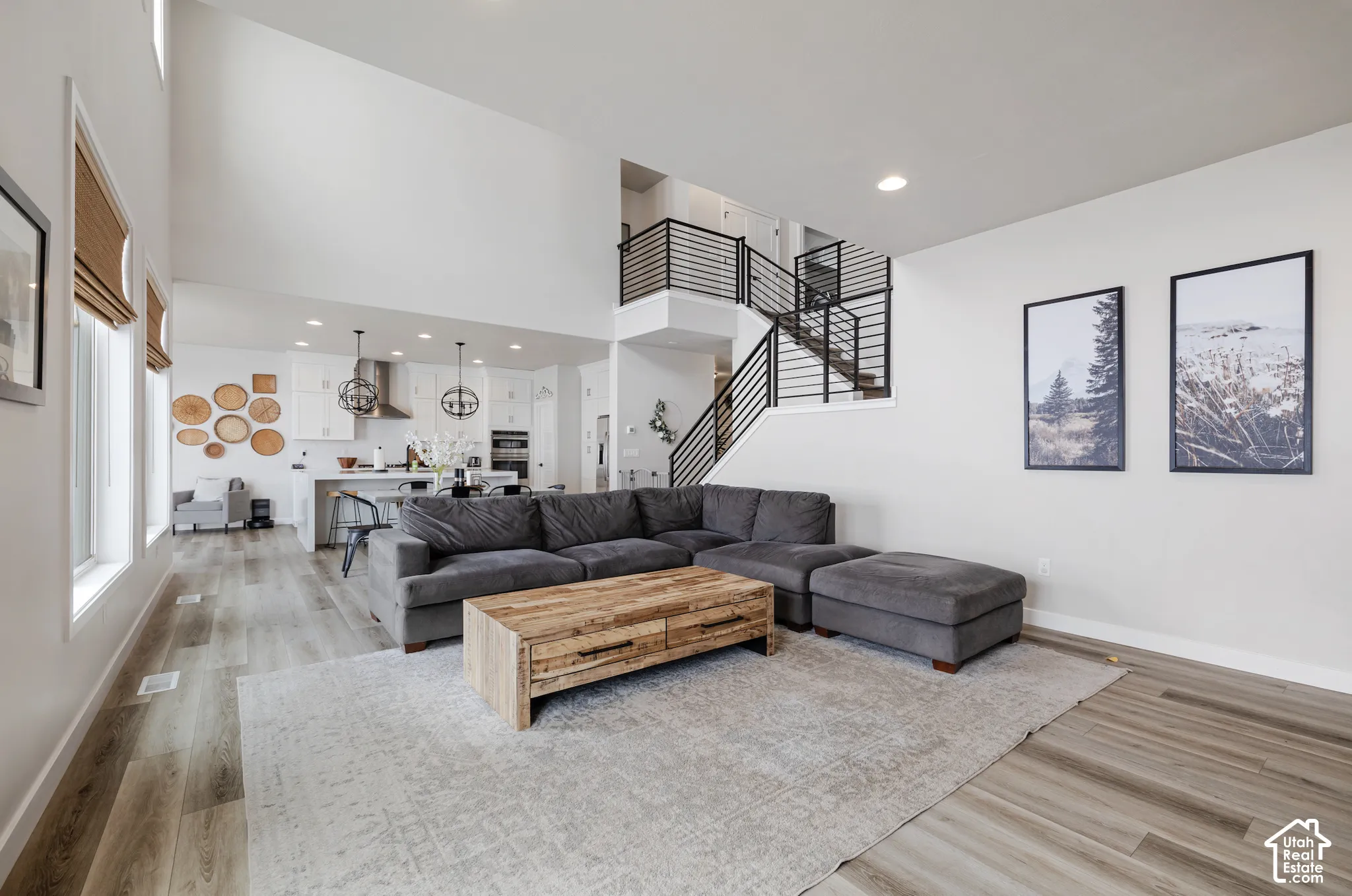 Vaulted ceilings, wood-finish flooring, open-concept kitchen, modern baluster staircase, and recessed lighting