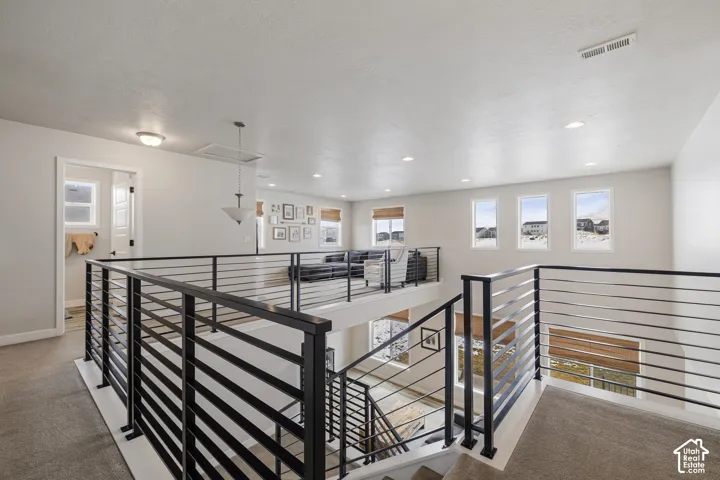 Open loft area with contemporary metal railings and recessed lighting