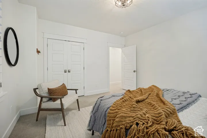 White paneled bi-fold closet doors with square hardware, neutral-toned carpeting, and a semi-flush mount ceiling light fixture