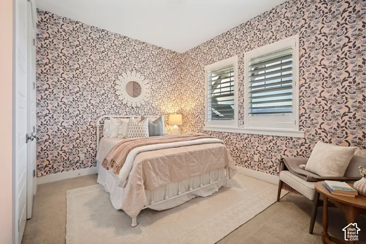 Floral pattern wallpaper, two windows with white plantation shutters, and a white interior door with dark hardware