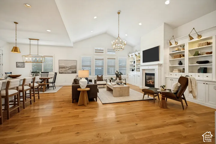 Vaulted ceiling, wood-finish flooring, built-in shelving, fireplace, and integrated lighting fixtures