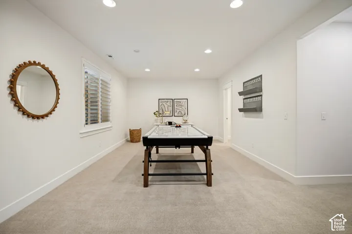 Recessed ceiling lighting, white walls, light-toned carpet flooring, window with white blinds, and built-in shelving