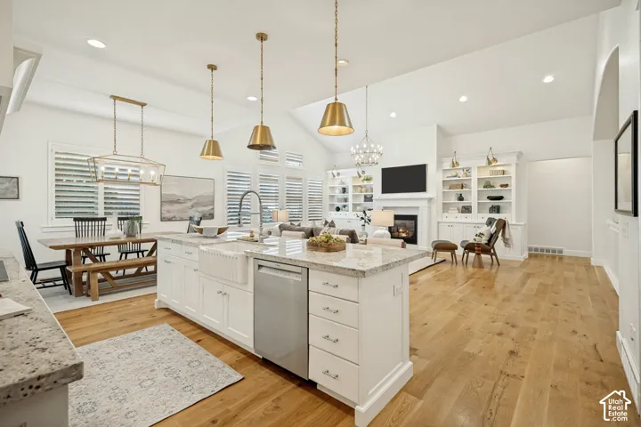 Open-concept living area featuring a kitchen island with stone countertops, a farmhouse sink, and integrated stainless steel appliances
