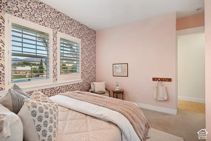 Dual windows with plantation shutters, patterned accent wall, light pink wall finishes, and carpeting