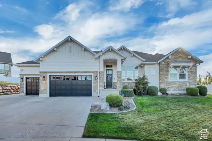 Exterior featuring mixed material facade, gabled rooflines, two attached garages, a concrete driveway, and front landscaping