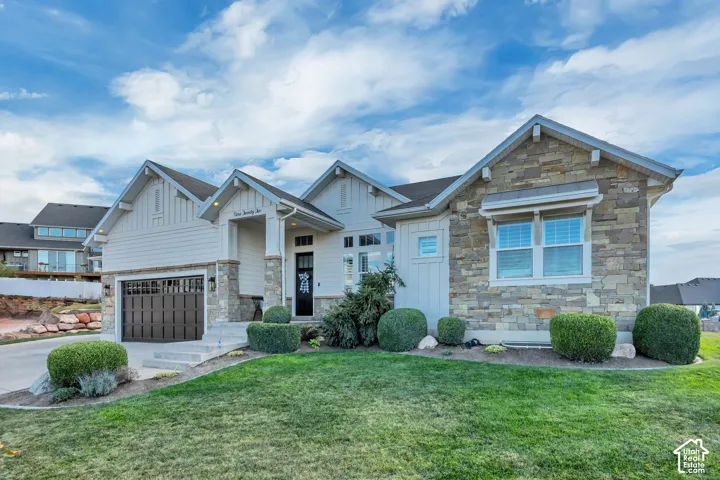 Exterior featuring horizontal siding, stone veneer accents, a dark garage door, and a covered entry