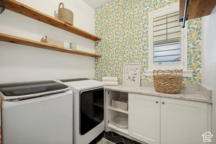 Laundry area featuring a window, wood-finish open shelving, white cabinetry with silver hardware, a light-toned countertop, and patterned wallpaper