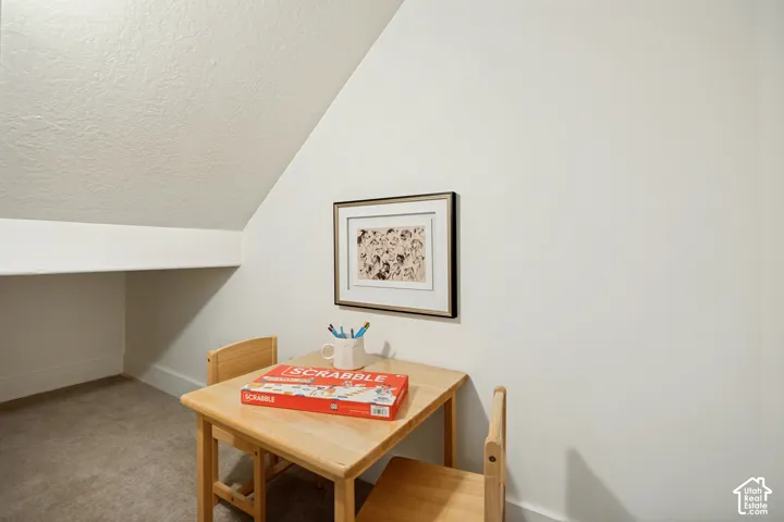 Recessed alcove with carpet flooring and sloped ceiling
