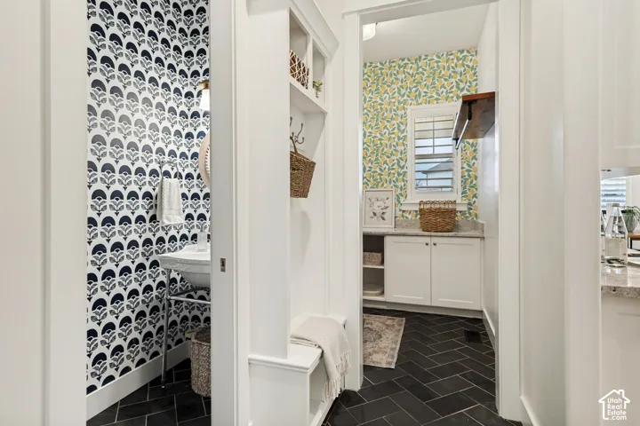 Herringbone tile flooring, built-in shelving, white cabinetry with countertops, window with privacy blinds, and a built-in bench