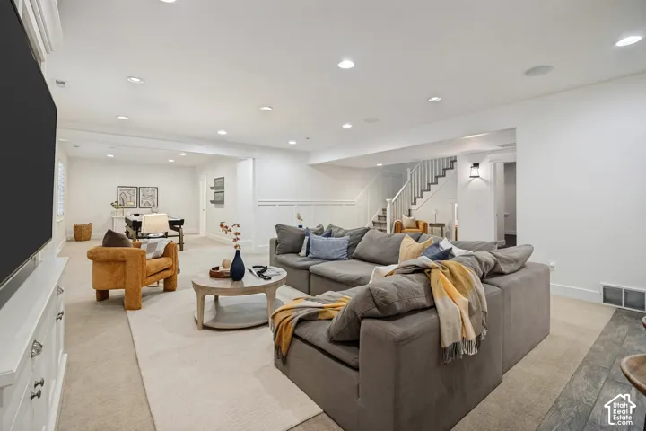 Recessed lighting, wainscoting, staircase with white risers, wall sconce, and built-in cabinetry