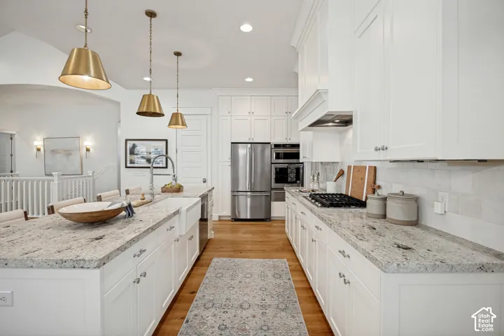 Kitchen featuring white cabinetry, light-toned countertops, hardwood flooring, and stainless steel appliances