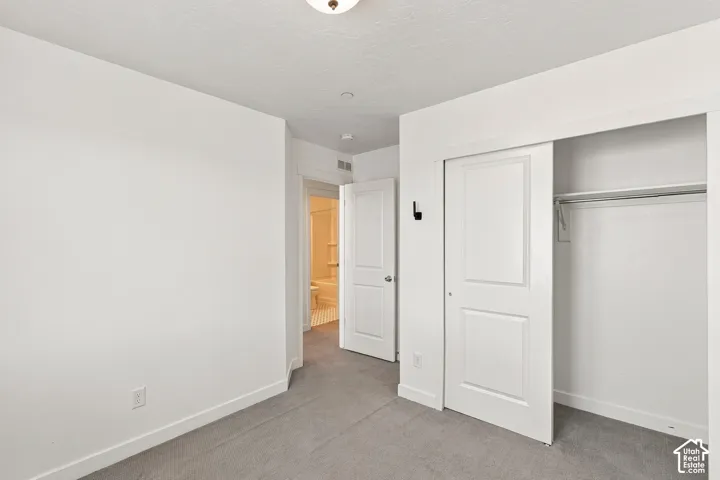 White interior walls, gray carpet flooring, white sliding closet doors, white interior door, and a flush mount ceiling light
