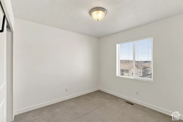Primary bedroom with carpeted flooring, white walls, and a window with horizontal blinds