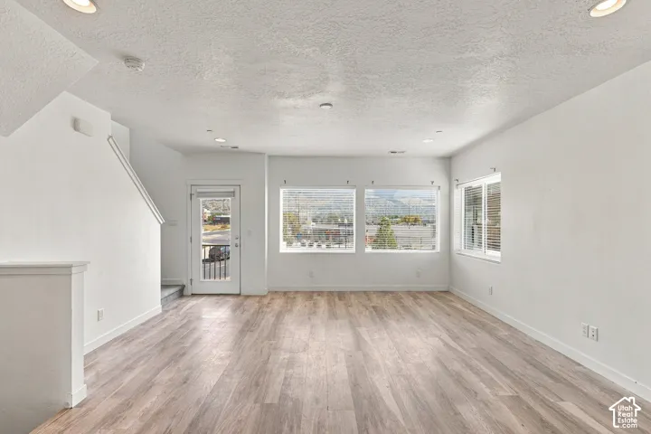 Spacious interior with wood-finish flooring, white walls, and recessed lighting
