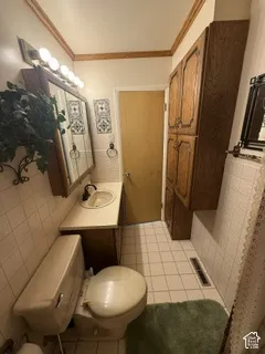 Bathroom featuring a single vanity, a built-in toilet, a tiled shower surround, and extensive wood-finish cabinetry