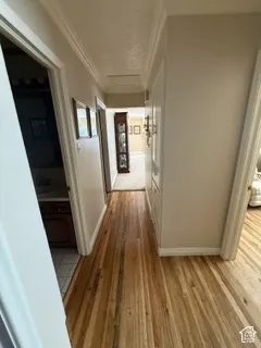 Wood-finish flooring throughout, crown molding, and built-in hallway cabinetry
