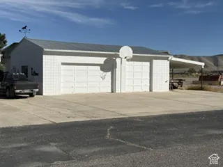 three-car garage with white paneled doors, metal roofing, and attached carport