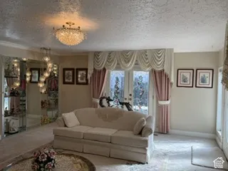 Recessed ceiling with crystal chandelier, wall-mounted display cabinetry with mirrored backing, and decorative glass patio doors