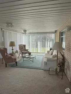 Enclosed sunroom featuring a brick accent wall, full-height windows, a slatted ceiling, and ceiling fans