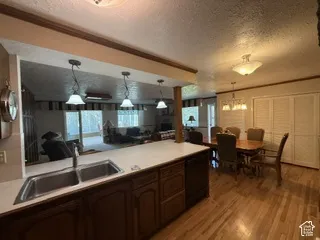 Kitchen featuring a double basin stainless steel sink, solid surface countertops, wood cabinetry, and pendant lighting