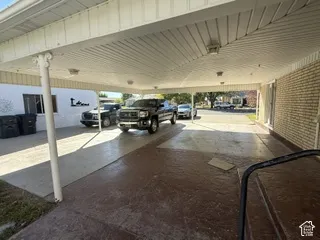Covered parking structure with a textured concrete surface, supported by white posts