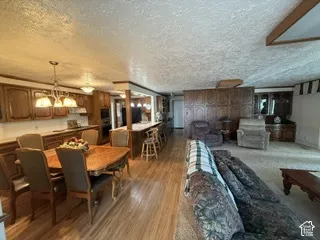 Open-concept living area with wood-finish flooring, a kitchen featuring wood cabinetry, a built-in oven, and a breakfast bar