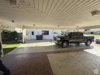 Covered carport with concrete flooring and metal roof structure, providing protected parking for multiple vehicles