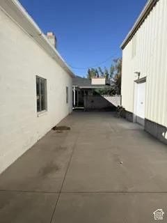 Paved concrete corridor with a stucco-clad building and corrugated metal siding structure