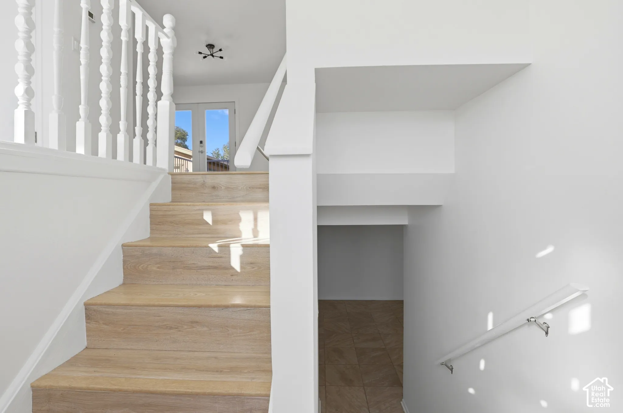 Wood-finish stairs with white baluster railing and a modern light fixture