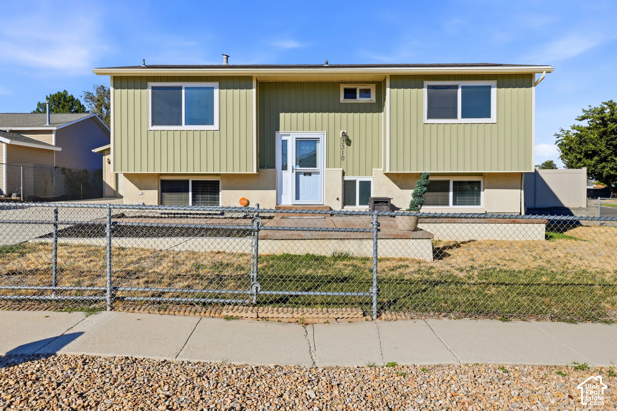 Split-level residence featuring light green vertical siding, contrasting with a neutral-toned foundation