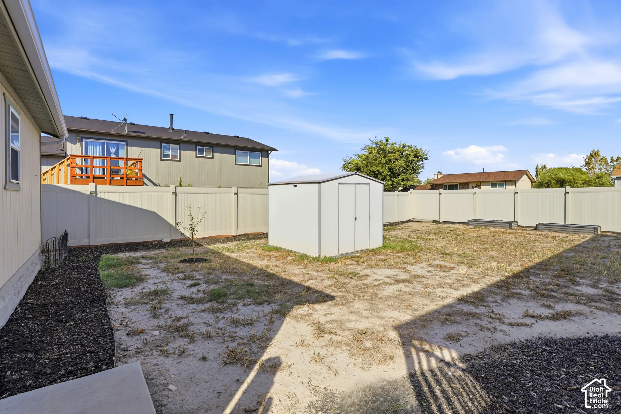 Spacious backyard featuring a metal storage shed, full perimeter fencing, and mulched planting beds
