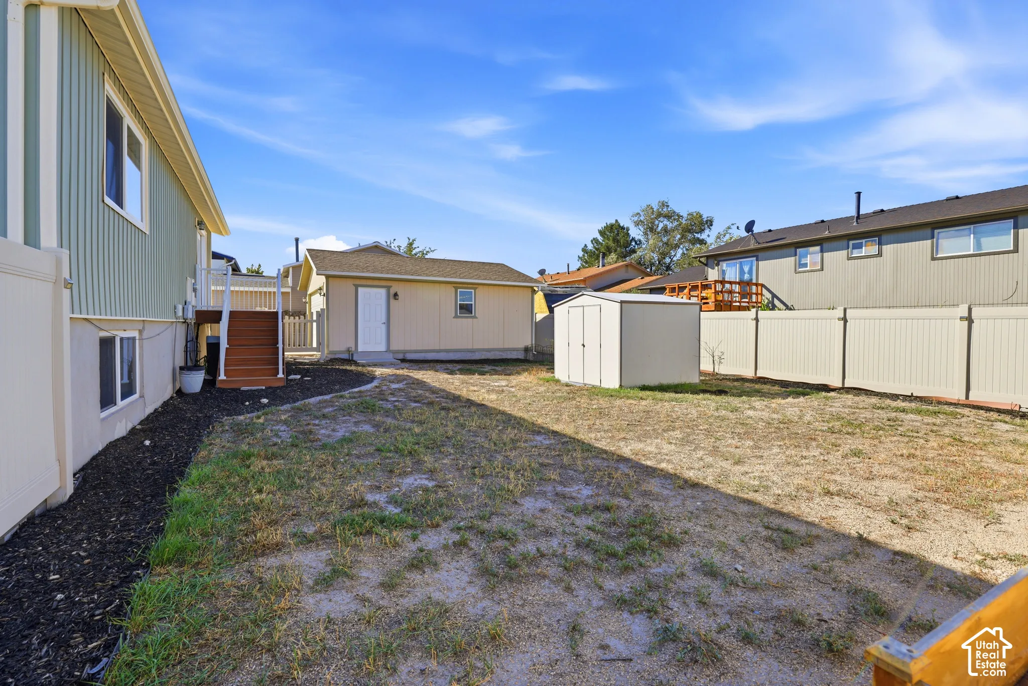 Expansive backyard featuring a detached accessory building, a storage shed, and a privacy fence