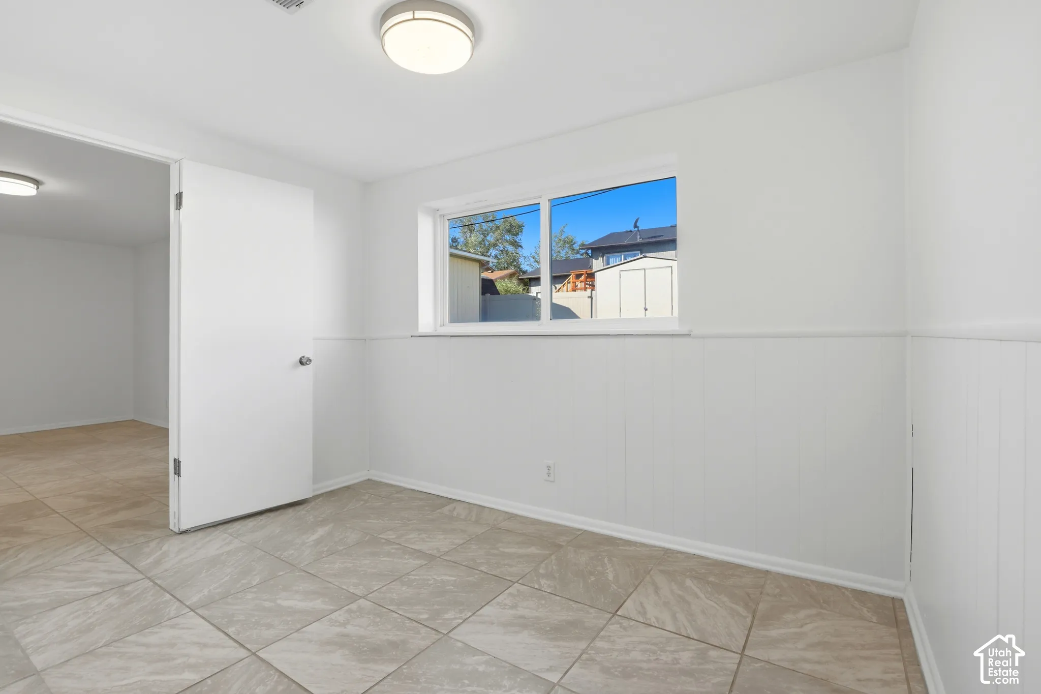 Recessed lighting, tile flooring, window with white trim, and wainscoting