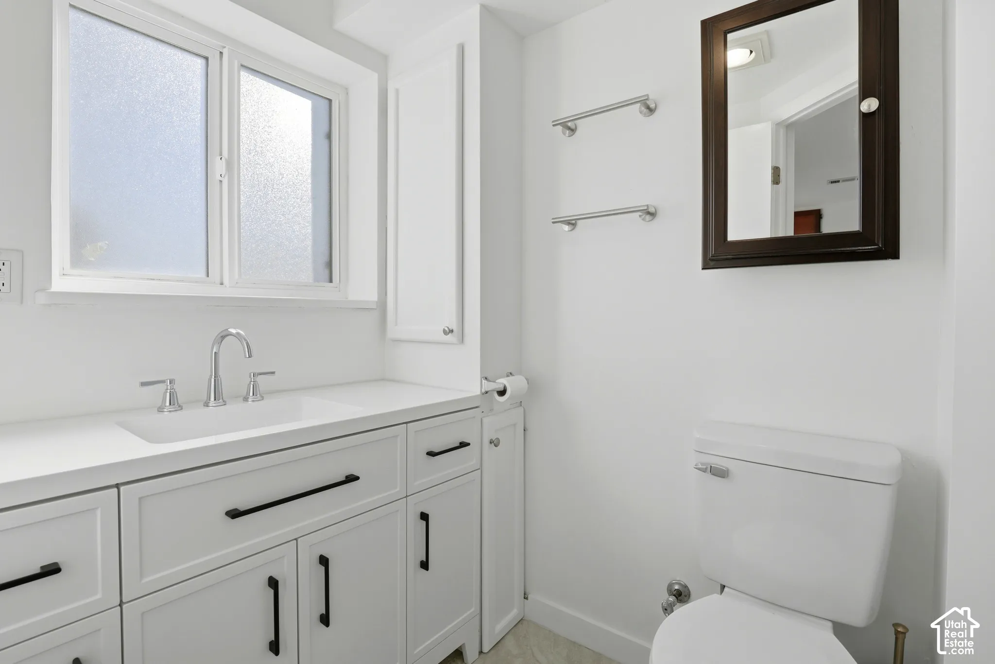 White vanity with integrated sink, chrome faucet, and black hardware