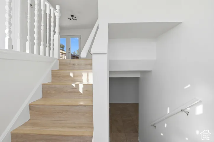 Wood-finish stairs with white baluster railing and a modern light fixture