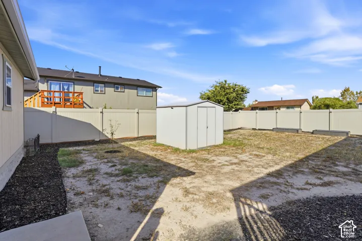 Spacious backyard featuring a metal storage shed, full perimeter fencing, and mulched planting beds