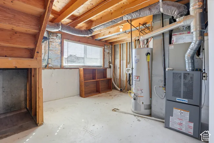 Exposed wood ceiling joists, concrete flooring, and a single window with blinds