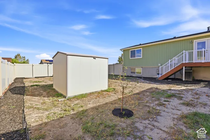 Backyard featuring a metal storage shed, a tan privacy fence, and a raised wooden deck with white railings