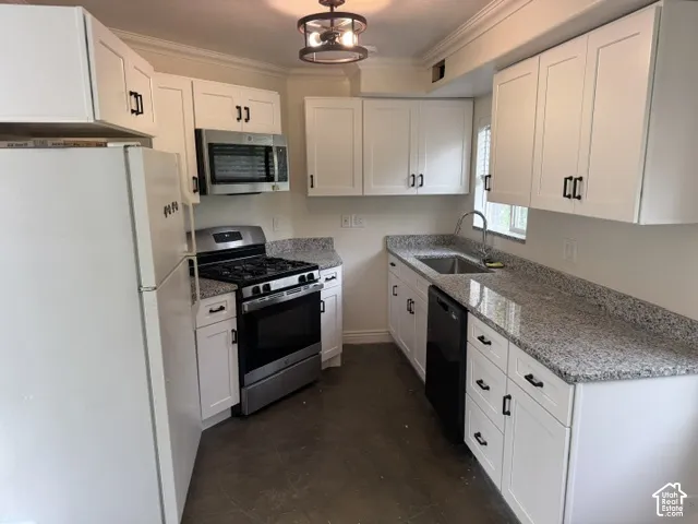 White shaker-style cabinetry with dark hardware, granite countertops, stainless steel gas range, and built-in microwave